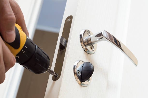Worker installing or repairing new lock and door knob with screwdriver. Locksmith repair or install the door lock in house.