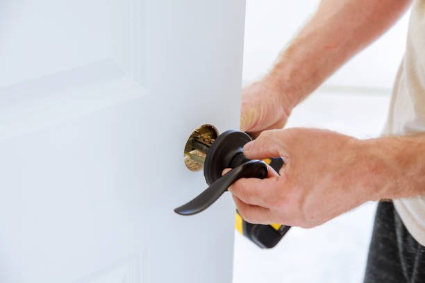 Install the door handle with a lock, Carpenter tighten the screw, using an electric drill screwdriver, close-up.