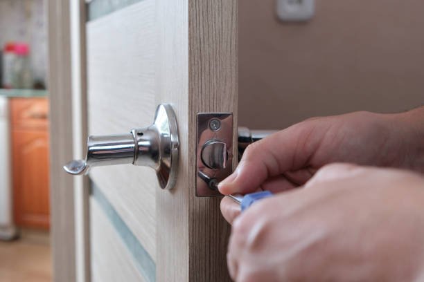 Man repairs lock interior door with screwdriver